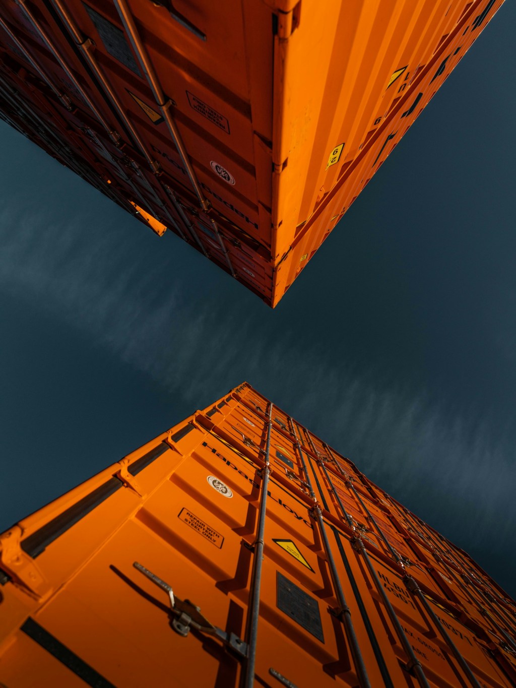 Stacked orange shipping containers against a blue sky